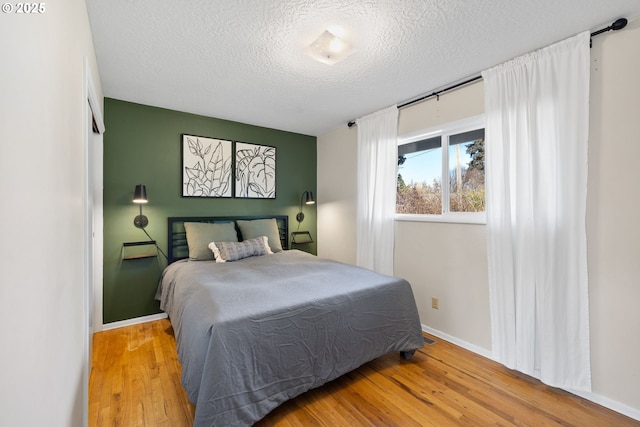 bedroom with light wood-type flooring and a textured ceiling