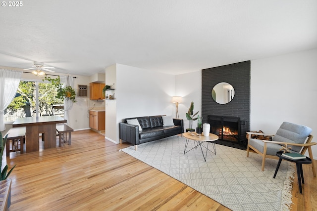 living room with light hardwood / wood-style flooring, ceiling fan, and a fireplace