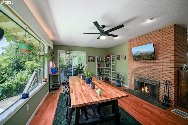 7360 SE Imperial Ct, Milwaukie, OR 97222 - dining room with a brick fireplace, a ceiling fan, wood finished floors, and a textured ceiling