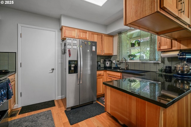 7360 SE Imperial Ct, Milwaukie, OR 97222 - kitchen featuring stainless steel fridge with ice dispenser, tasteful backsplash, light wood-type flooring, a peninsula, and dark stone countertops