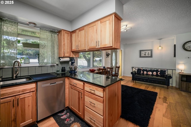7360 SE Imperial Ct, Milwaukie, OR 97222 - kitchen featuring stainless steel dishwasher, light wood finished floors, tasteful backsplash, a peninsula, and dark stone counters