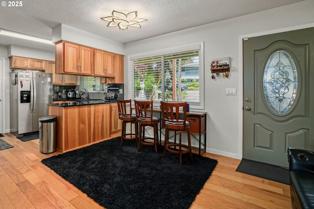 7360 SE Imperial Ct, Milwaukie, OR 97222 - kitchen with stainless steel refrigerator with ice dispenser, light wood-style floors, dark countertops, a peninsula, and a textured ceiling