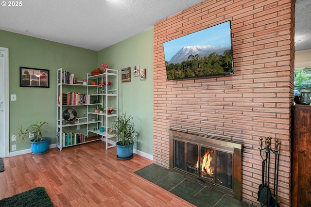 7360 SE Imperial Ct, Milwaukie, OR 97222 - living room with wood finished floors, a textured ceiling, and a brick fireplace