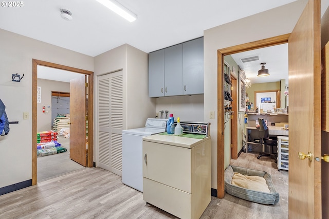 laundry room featuring cabinets, light wood-type flooring, and washing machine and clothes dryer