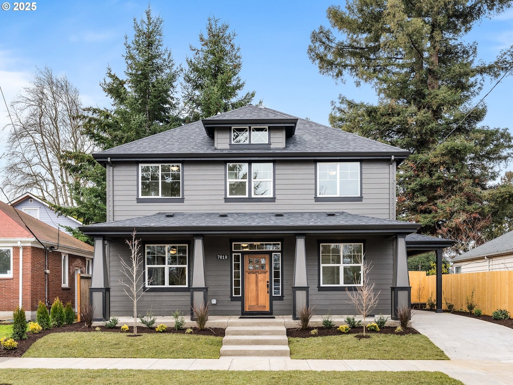 traditional style home featuring a shingled roof, covered porch, fence, and concrete driveway