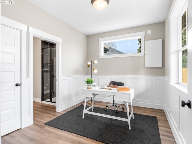 office with wainscoting, light wood-type flooring, and a healthy amount of sunlight