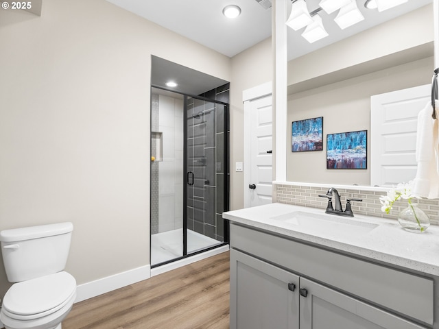 full bathroom featuring toilet, decorative backsplash, a stall shower, vanity, and wood finished floors