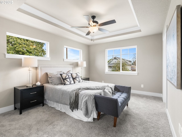 bedroom with baseboards, a tray ceiling, and light colored carpet