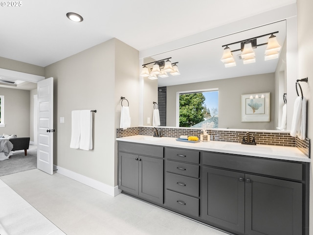 ensuite bathroom featuring double vanity, tasteful backsplash, and a sink