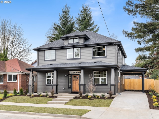 traditional style home featuring a shingled roof, concrete driveway, fence, a carport, and a front lawn