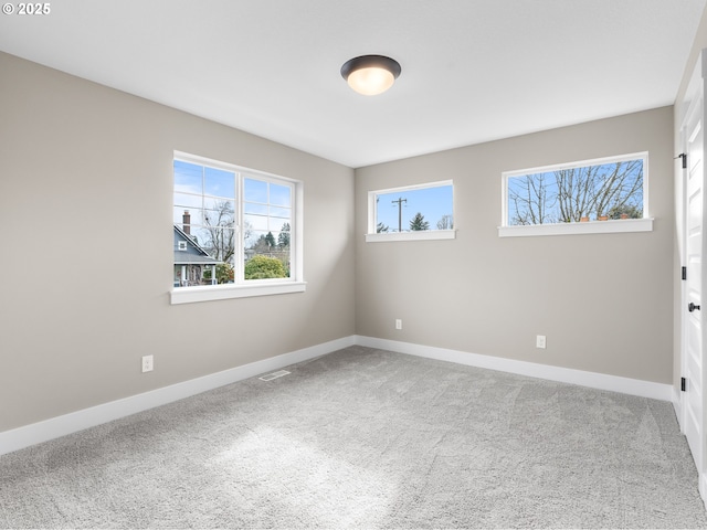 spare room with carpet flooring, visible vents, and baseboards