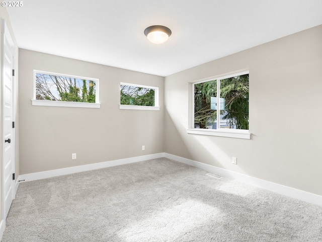 unfurnished room with baseboards, visible vents, and light colored carpet