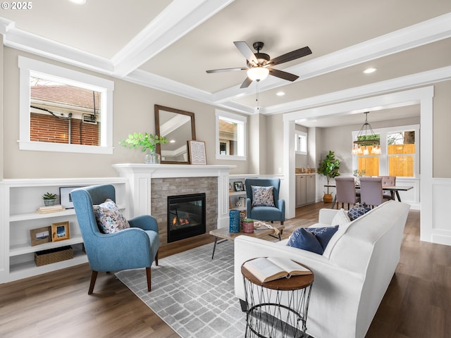 living room with a glass covered fireplace, wainscoting, wood finished floors, and a decorative wall