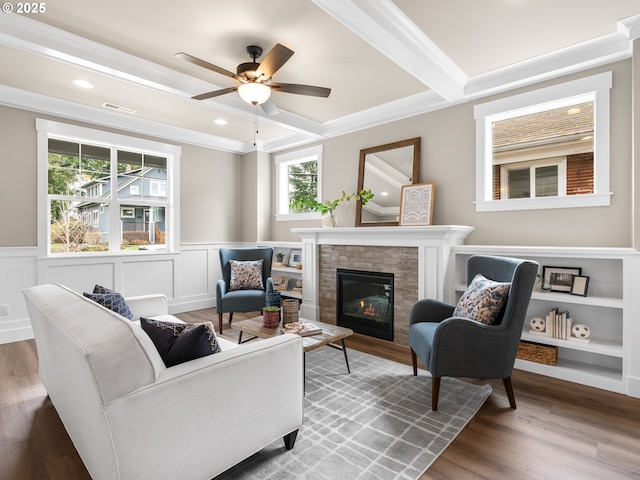 living area featuring a wainscoted wall, beam ceiling, and wood finished floors