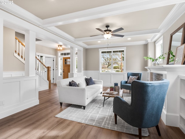 living area with wainscoting, wood finished floors, stairs, a decorative wall, and beam ceiling