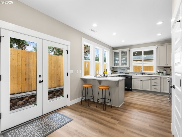 kitchen with visible vents, a breakfast bar, a peninsula, light countertops, and french doors