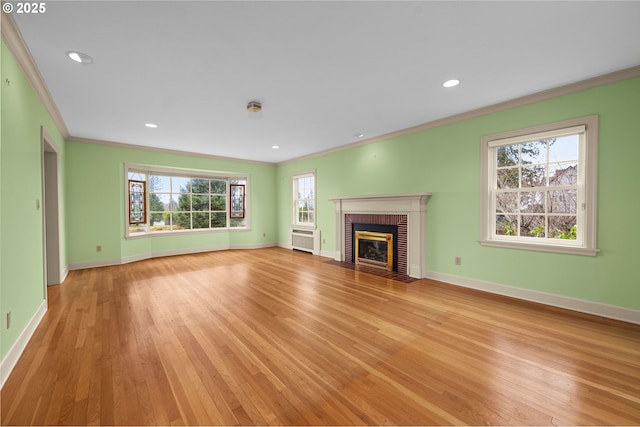 unfurnished living room featuring ornamental molding, a fireplace, light wood-style flooring, and baseboards