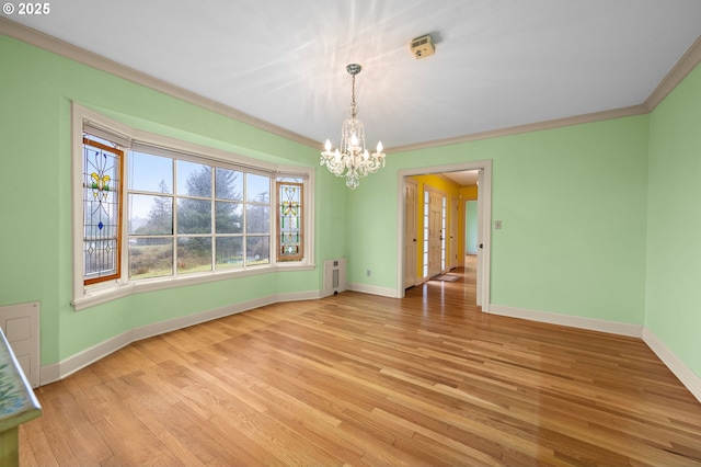 spare room with baseboards, radiator, light wood-style flooring, crown molding, and a chandelier