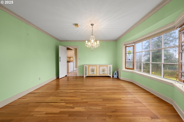 unfurnished dining area with ornamental molding, an inviting chandelier, light wood-style flooring, and baseboards