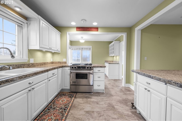 kitchen with stainless steel gas range, recessed lighting, a sink, and white cabinets