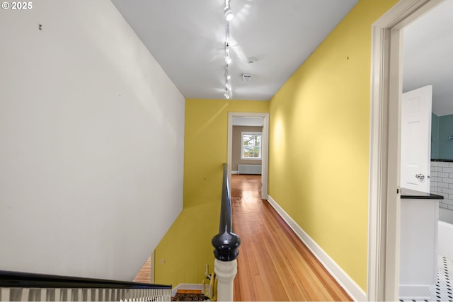 hall featuring rail lighting, baseboards, and wood finished floors