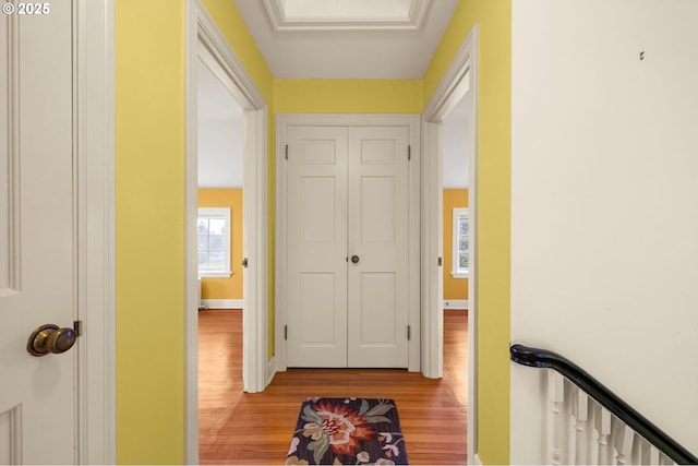 hall with light wood-style floors, attic access, and baseboards