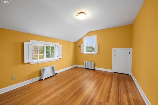 bonus room featuring lofted ceiling, light wood finished floors, baseboards, and radiator