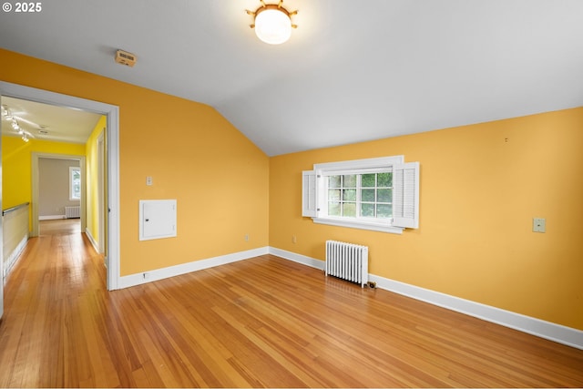 additional living space with lofted ceiling, light wood finished floors, baseboards, and radiator