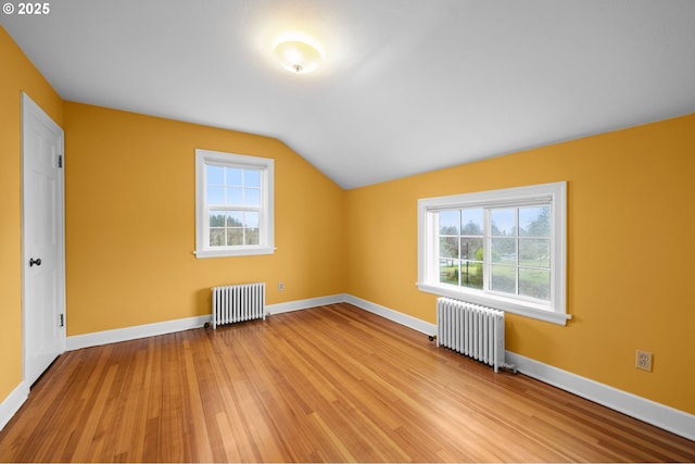 additional living space with radiator heating unit, a wealth of natural light, and light wood-style floors