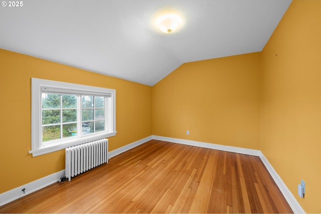 bonus room featuring baseboards, vaulted ceiling, radiator heating unit, and wood finished floors