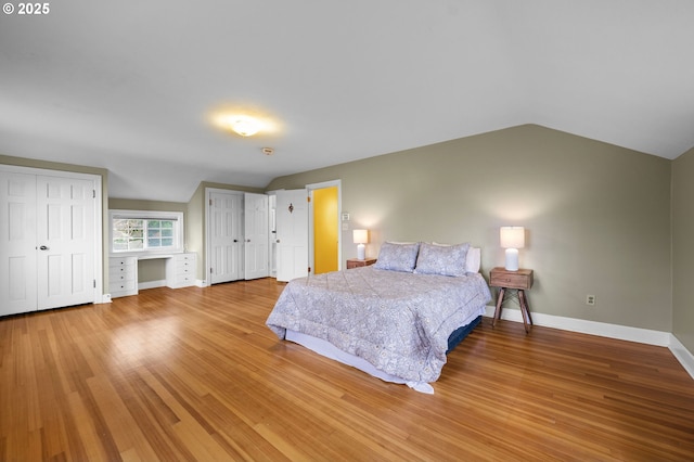 bedroom with light wood-style floors, lofted ceiling, and baseboards