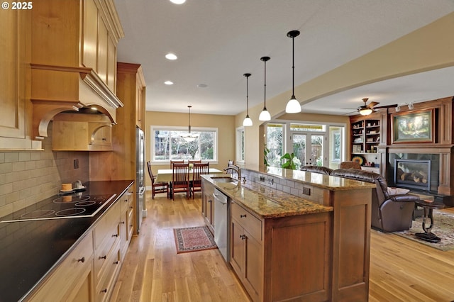 kitchen with a tile fireplace, open floor plan, appliances with stainless steel finishes, and light wood-type flooring