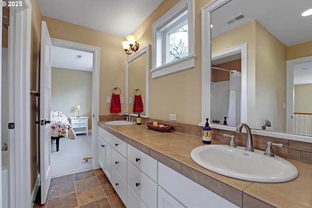 full bath featuring a sink, visible vents, double vanity, and stone finish flooring