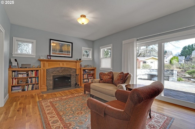 sitting room featuring a brick fireplace and light wood-style flooring