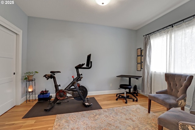 workout room with baseboards and light wood-style floors