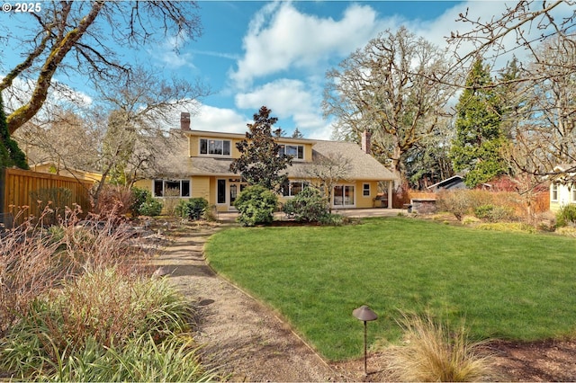 rear view of house featuring a patio, a chimney, a yard, and fence