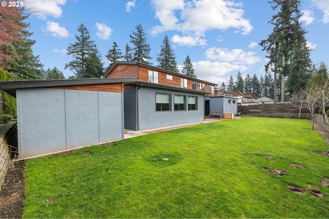 rear view of house featuring a yard, stucco siding, and a fenced backyard