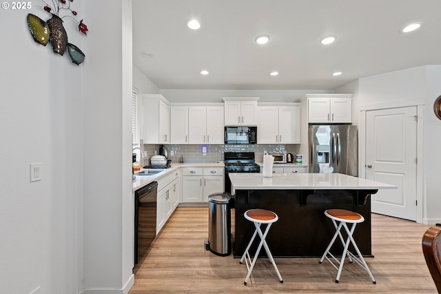 2504 Brackenfern Rd, Eugene, OR 97403 - kitchen featuring black appliances, a sink, light wood-style flooring, a center island, and recessed lighting