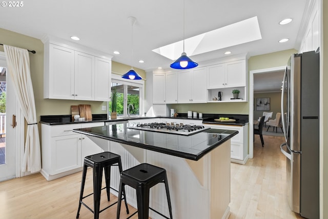 6025 SW Spruce Ave, Beaverton, OR 97005 - kitchen with stainless steel appliances, a skylight, dark countertops, white cabinetry, and a kitchen bar
