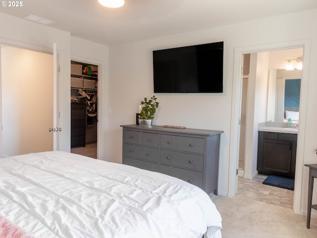 bedroom featuring ensuite bathroom, a walk in closet, light carpet, and a closet