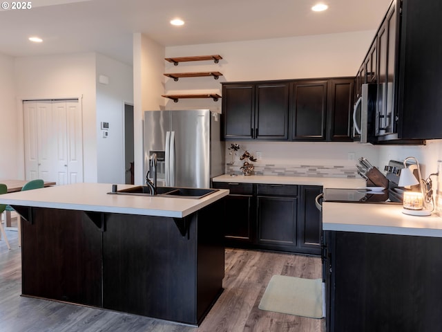 kitchen featuring stainless steel appliances, a kitchen island with sink, a kitchen breakfast bar, and light hardwood / wood-style floors