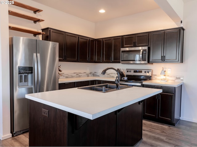 kitchen with appliances with stainless steel finishes, sink, wood-type flooring, and a center island with sink