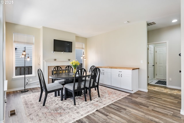 dining room featuring a wealth of natural light, visible vents, baseboards, and wood finished floors