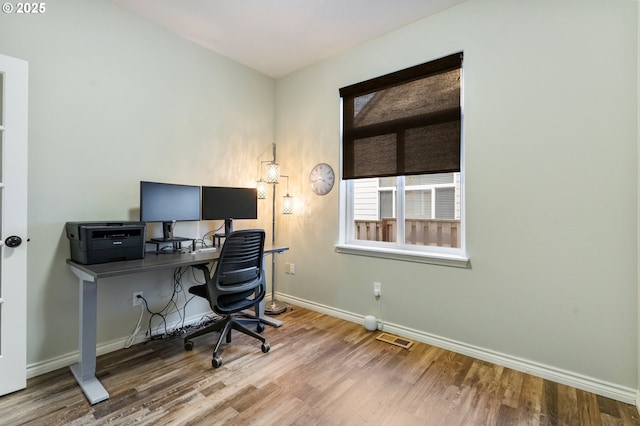 office space with baseboards, visible vents, and wood finished floors