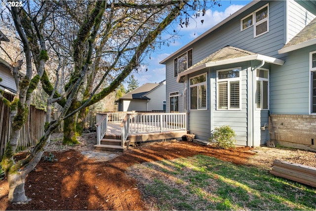 rear view of property featuring a deck, a shingled roof, and fence