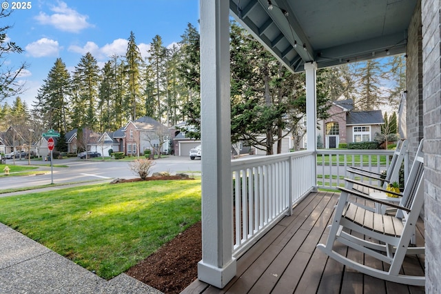 deck featuring covered porch, a residential view, and a yard