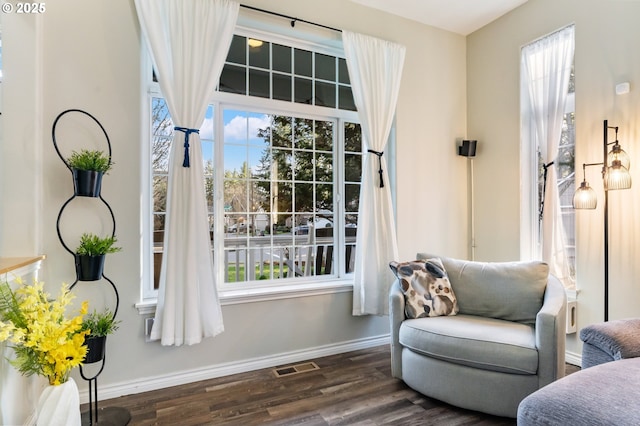 sitting room with wood finished floors, visible vents, and baseboards