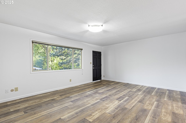 unfurnished room with a textured ceiling, baseboards, and wood-type flooring