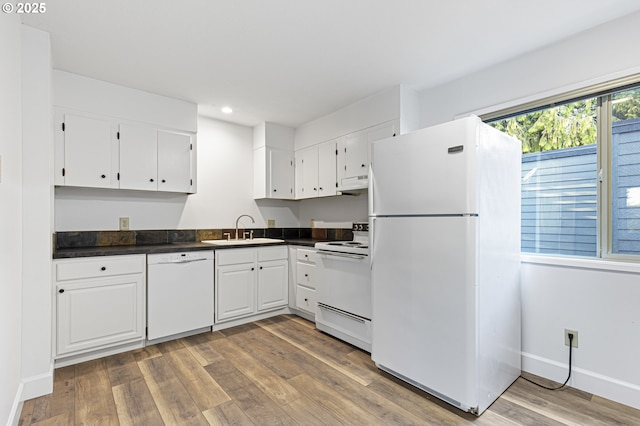 kitchen featuring white appliances, light wood-style flooring, a sink, white cabinetry, and dark countertops