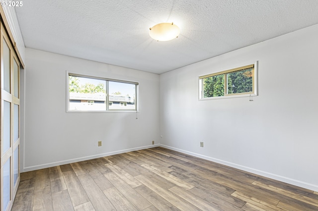 unfurnished room with baseboards, a textured ceiling, and wood finished floors